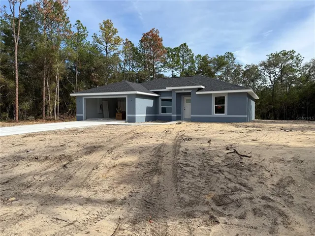 a front view of a house with a yard covered with trees