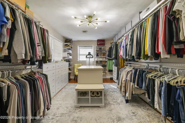 a view of walk in closet with clothes and shoes
