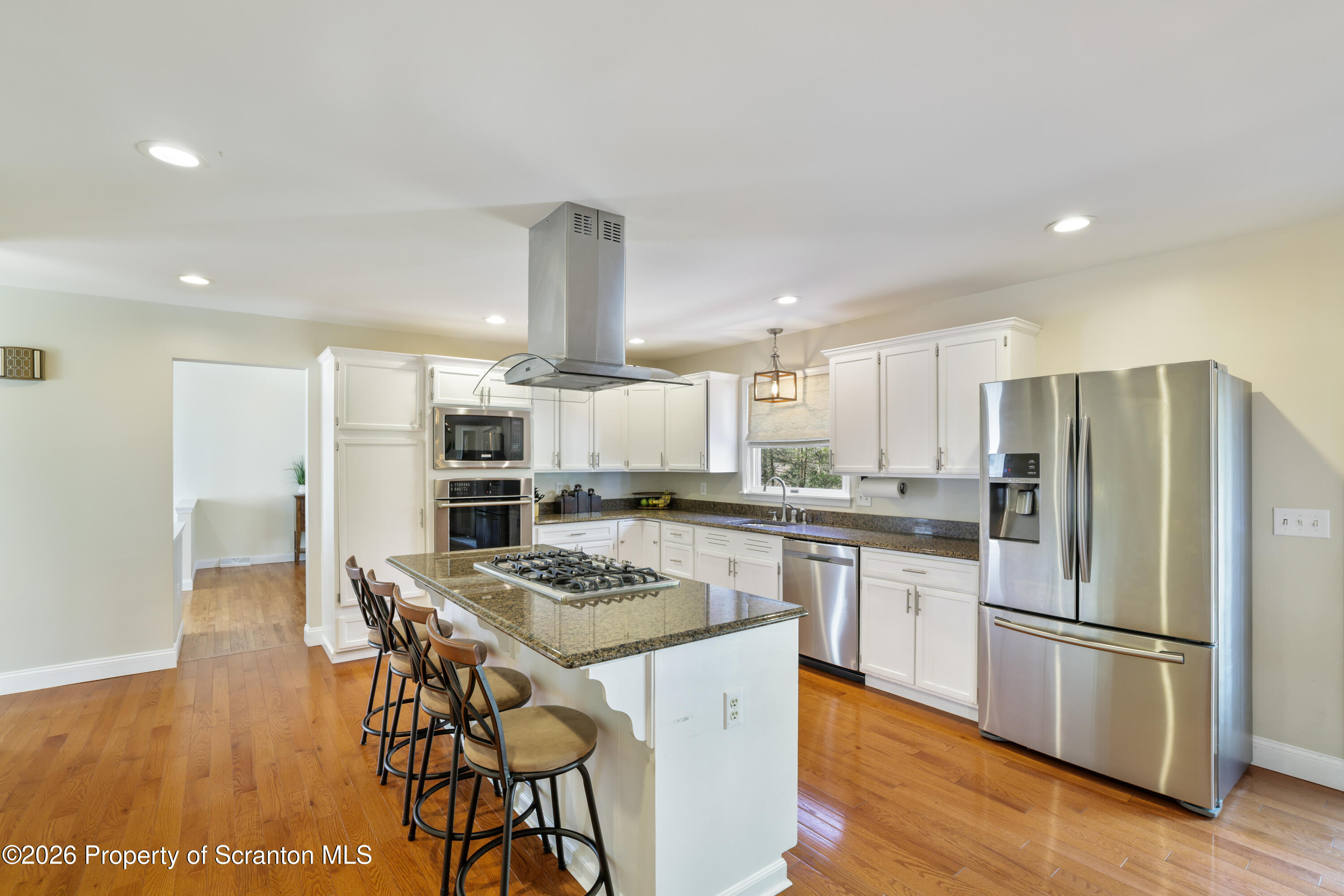 3 Old Mill Road Jermyn, PA 18433 - Photo 9 of 57 a kitchen with stainless steel appliances kitchen island granite countertop a refrigerator a stove a sink dishwasher and white cabinets with wooden floor
