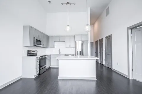 a kitchen with stainless steel appliances kitchen island wooden floors and white cabinets