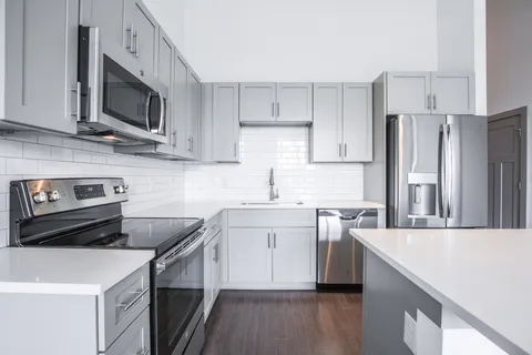 a kitchen with stainless steel appliances a sink a stove a microwave a refrigerator a sink and cabinets