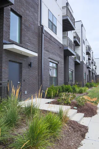 a view of a brick house with a yard and plants