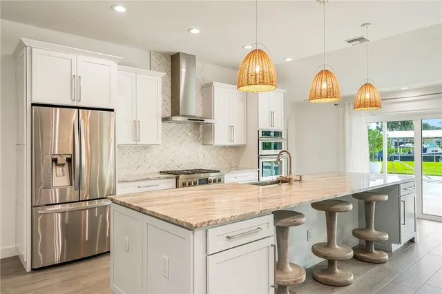 a kitchen with stainless steel appliances granite countertop a sink a stove and refrigerator