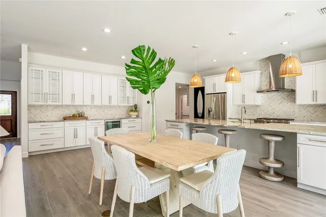 a kitchen with stainless steel appliances kitchen island granite countertop a table chairs and a refrigerator