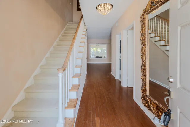a view of a hallway with wooden floor and staircase