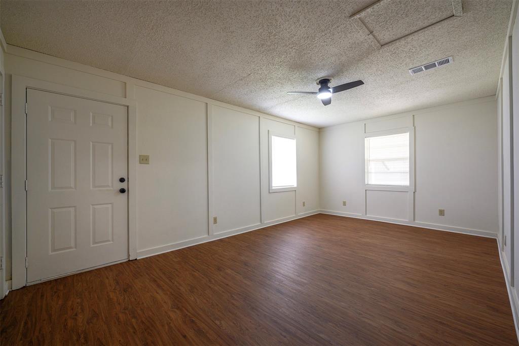 820 North Ave A Springtown, TX 76082 - Photo 15 of 27 Spacious room featuring wood-finish flooring, white walls with wainscoting, two windows, and a ceiling fan