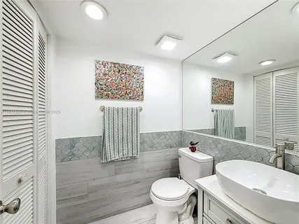 a bathroom with a granite countertop sink a toilet a mirror and shower