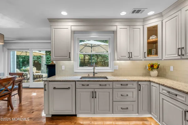 a kitchen with granite countertop a sink window and cabinets