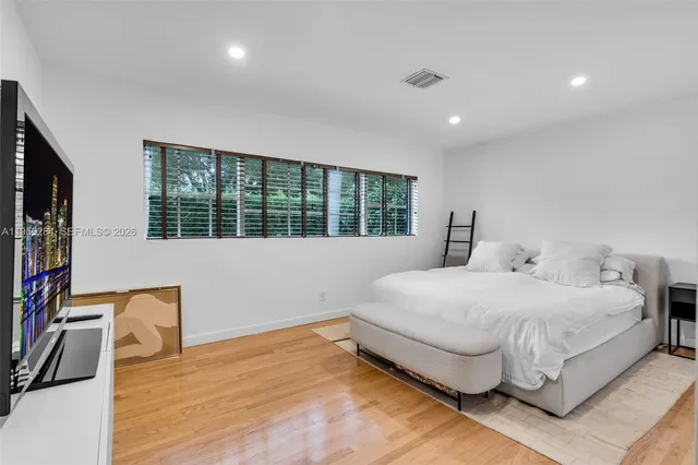a bedroom with a bed and a flat tv screen on dresser