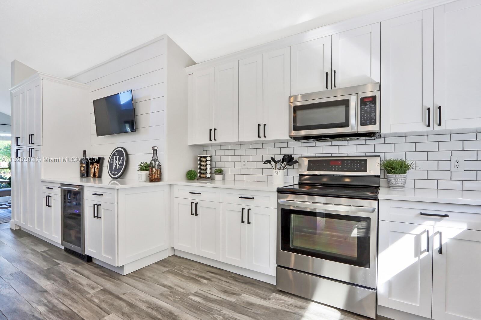 6122 Adams Street Jupiter, FL 33458 - Photo 12 of 59 a kitchen with white cabinets and appliances
