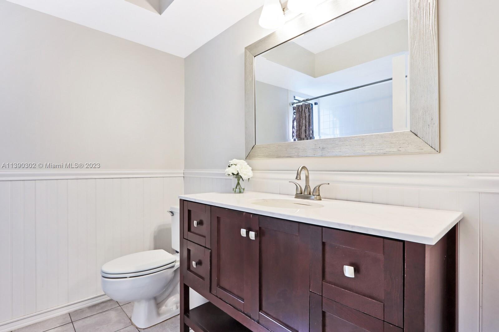 6122 Adams Street Jupiter, FL 33458 - Photo 20 of 59 a bathroom with a toilet a sink a vanity and mirror