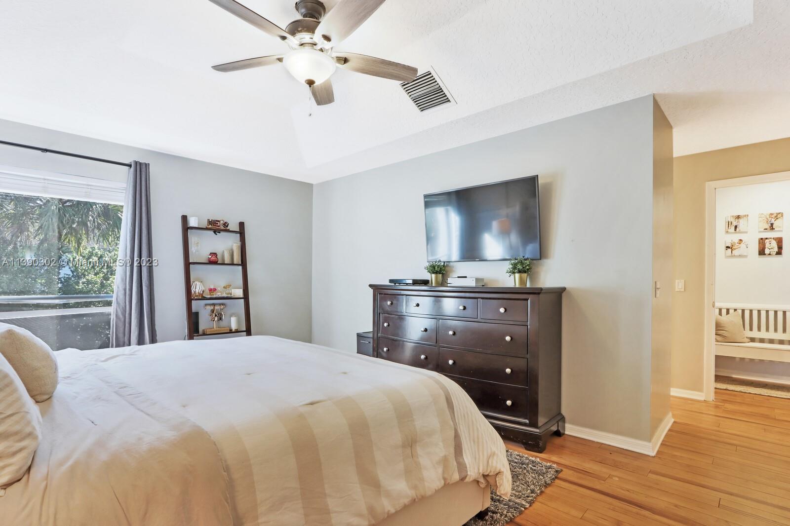 6122 Adams Street Jupiter, FL 33458 - Photo 23 of 59 a bedroom with a bed and a chandelier