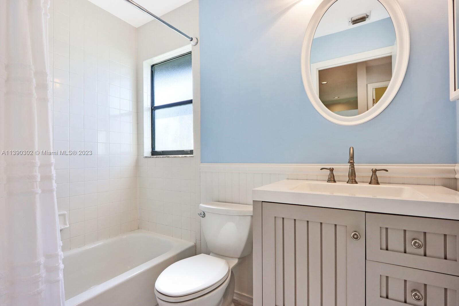 6122 Adams Street Jupiter, FL 33458 - Photo 28 of 59 a bathroom with a toilet sink vanity tub and mirror