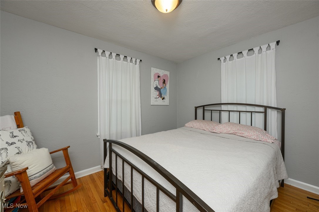 Bedroom with multiple windows and wood floors