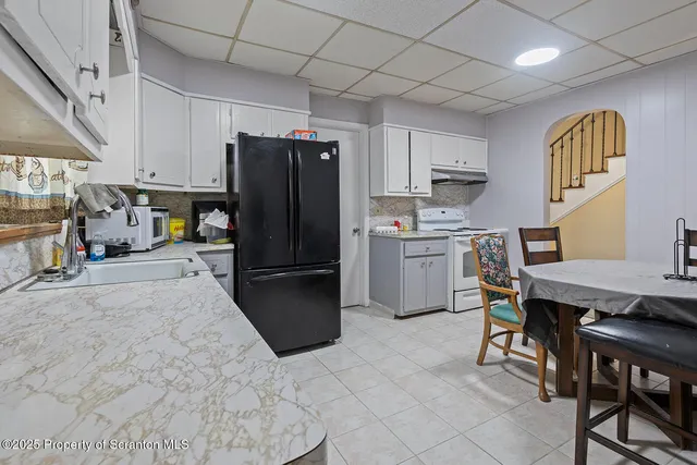 a kitchen with stainless steel appliances a refrigerator a stove a sink dishwasher with a dining table and chairs