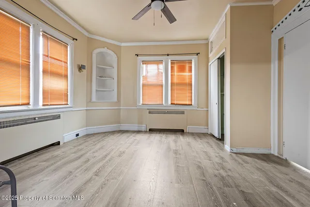 an empty room with wooden floor and windows
