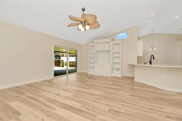 a view of an empty room with a window and kitchen view