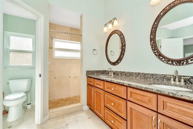 a bathroom with a granite countertop toilet a sink and a mirror