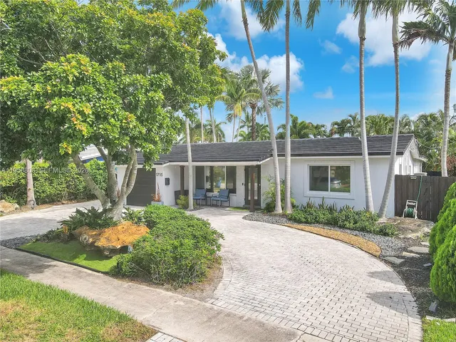 a front view of a house with a garden and trees
