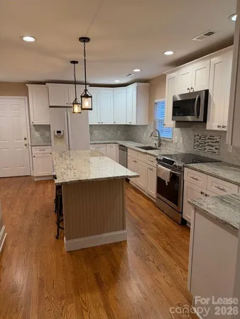 a kitchen with stainless steel appliances granite countertop a sink a stove top oven a counter space and cabinets