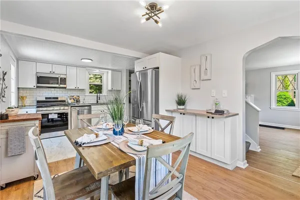 a open dining room with stainless steel appliances a dining table wooden floor and a kitchen view
