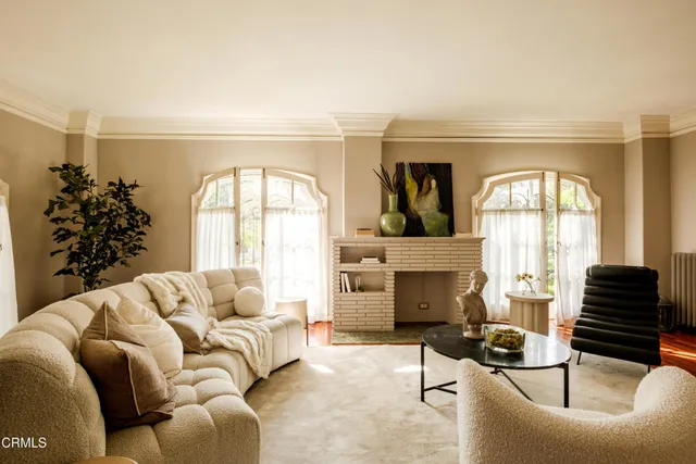 a living room with furniture a rug potted plant and a window