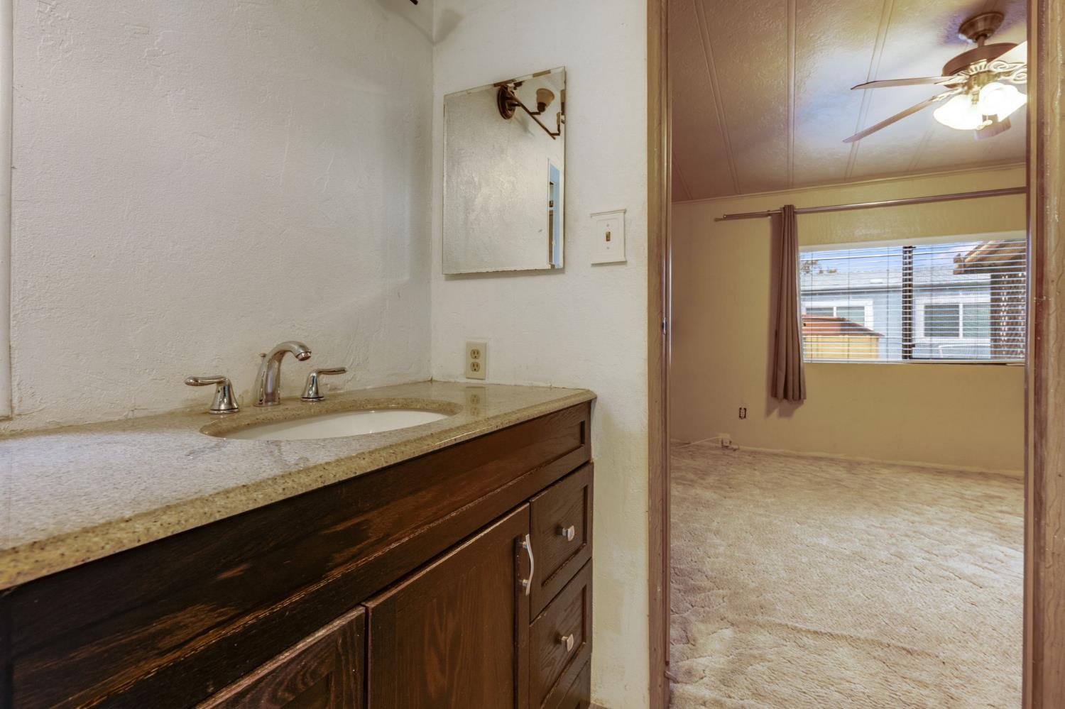443 Royal Crest Circle Rancho Cordova, CA 95670 - Photo 19 of 28 a bathroom with a granite countertop sink a toilet and a mirror