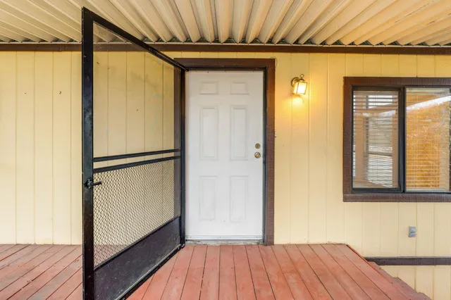 a view of a hallway with wooden floor and a bathroom