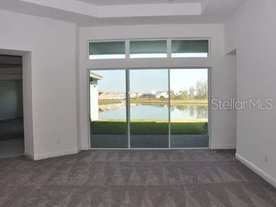 a view of an empty room with a window and a kitchen