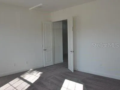 a view of an empty room with closet and mirror