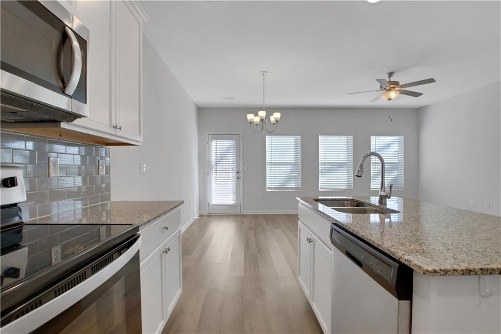 102 Jaxton Street Hoschton, GA 30548 - Photo 12 of 36 a kitchen with granite countertop stainless steel appliances a sink stove and cabinets