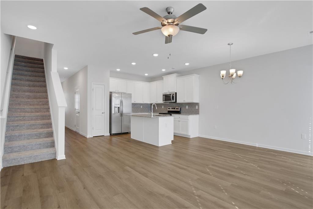 102 Jaxton Street Hoschton, GA 30548 - Photo 15 of 36 a view of an empty room and kitchen view with wooden floor