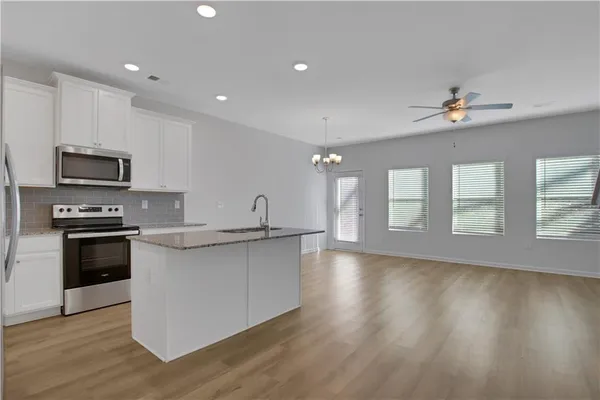 a kitchen with stainless steel appliances a stove top oven a sink a refrigerator a center island and cabinets