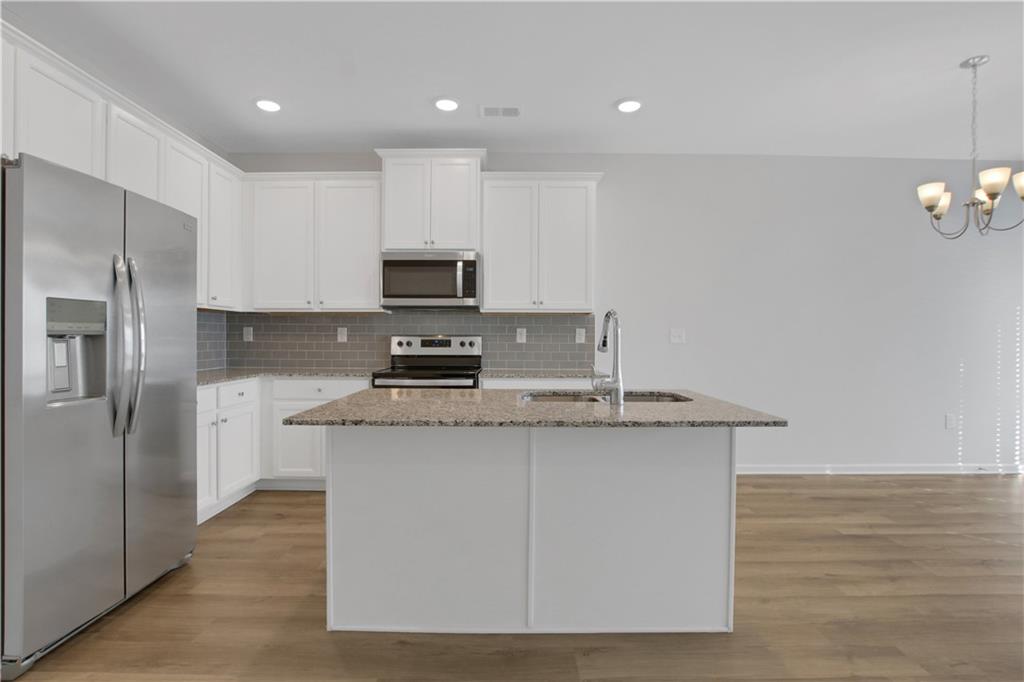 102 Jaxton Street Hoschton, GA 30548 - Photo 6 of 36 a kitchen with stainless steel appliances granite countertop a stove a sink a refrigerator and a microwave