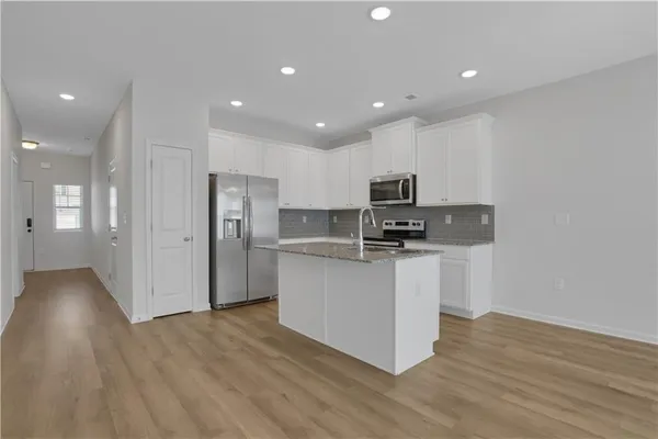 a kitchen with stainless steel appliances granite countertop a stove top oven a sink and a refrigerator