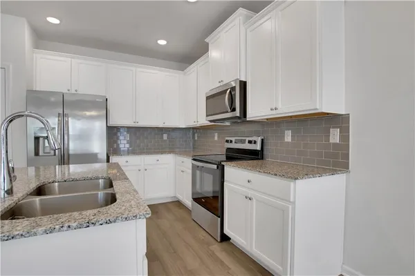 a kitchen with stainless steel appliances granite countertop a sink a stove and a refrigerator