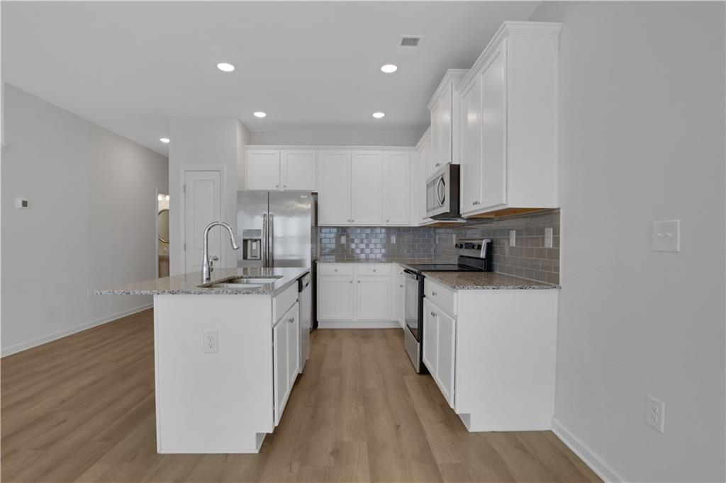 102 Jaxton Street Hoschton, GA 30548 - Photo 9 of 36 a kitchen with stainless steel appliances a sink stove and cabinets