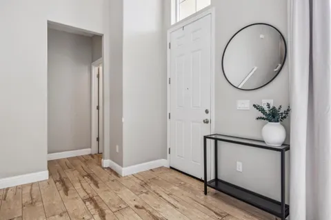 a view of a hallway with wooden floor and a mirror