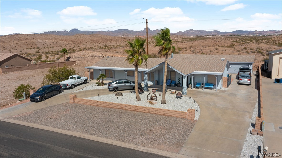 784 Pegasus Ranch Road Bullhead City, AZ 86429 - Photo 90 of 100 Single-story residence featuring a light blue exterior, a gabled roof, and two palm trees