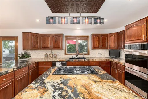 a large kitchen with stainless steel appliances granite countertop a stove a sink dishwasher and cabinets with wooden floor