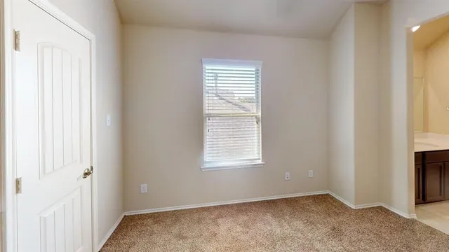 a view of an empty room with a window and a kitchen