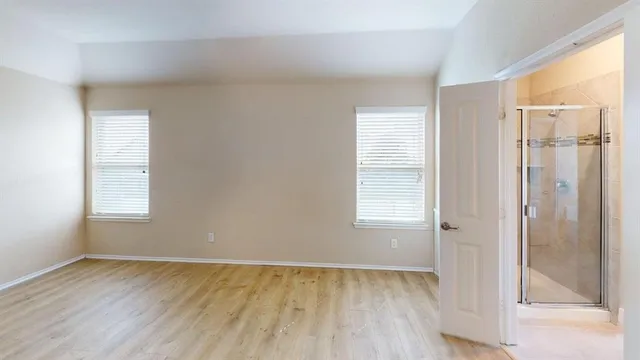 a view of an empty room with wooden floor and a window