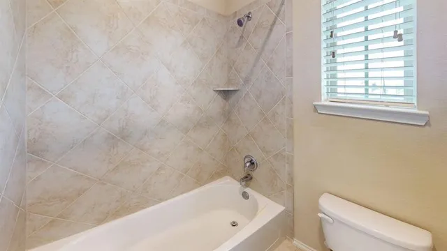a bathroom with a white bath tub and a toilet next to a window