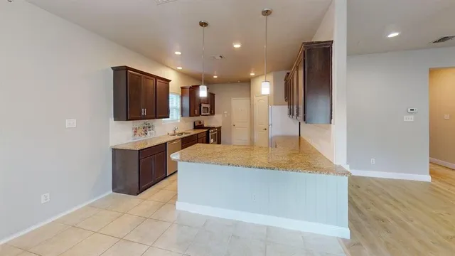 a large kitchen with stainless steel appliances a large counter top a stove a sink and a refrigerator