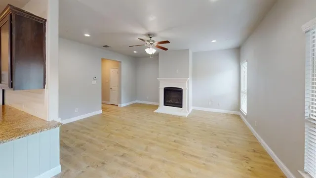a view of an empty room with kitchen and a window