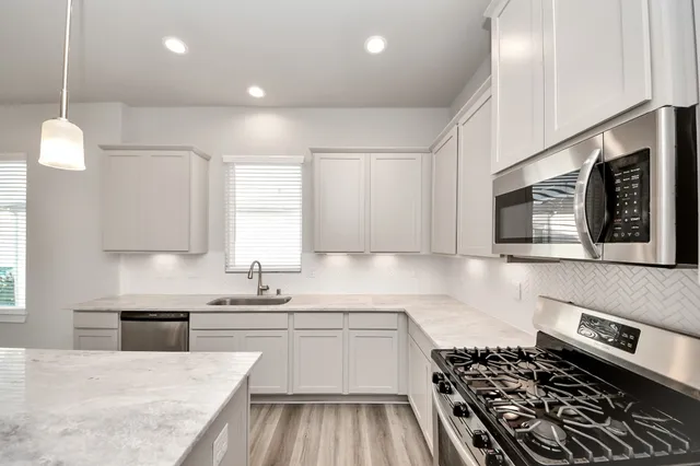 a kitchen with kitchen island granite countertop a sink stove and cabinets