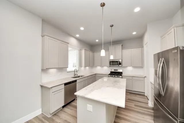 a kitchen with a refrigerator a sink a stove a microwave and white cabinets