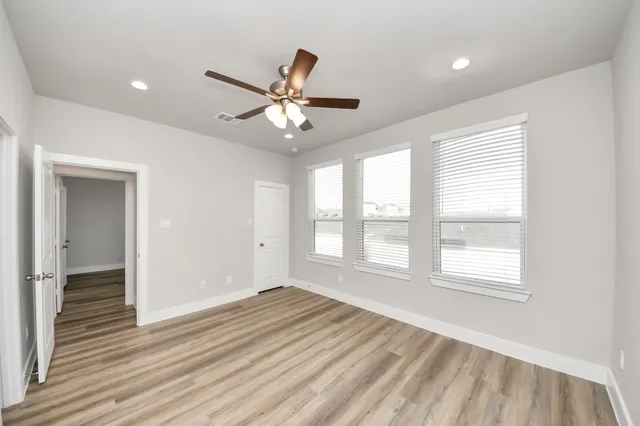 a view of an empty room with a window and wooden floor