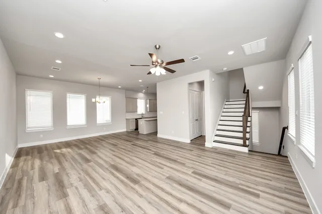 an empty room with wooden floor and a ceiling fan