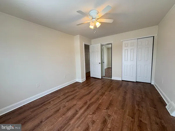 a view of an empty room with chandelier fan and wooden floor